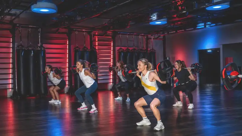 Groupe en squat avec barres pendant un cours de renforcement